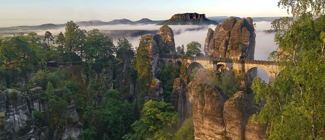 Brücke in einem Tal umgeben von Wolken