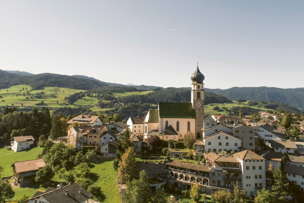 Außenansicht mit Kirchturm mit Blick auf das Romantik Hotel Turm in Völs in Südtirol