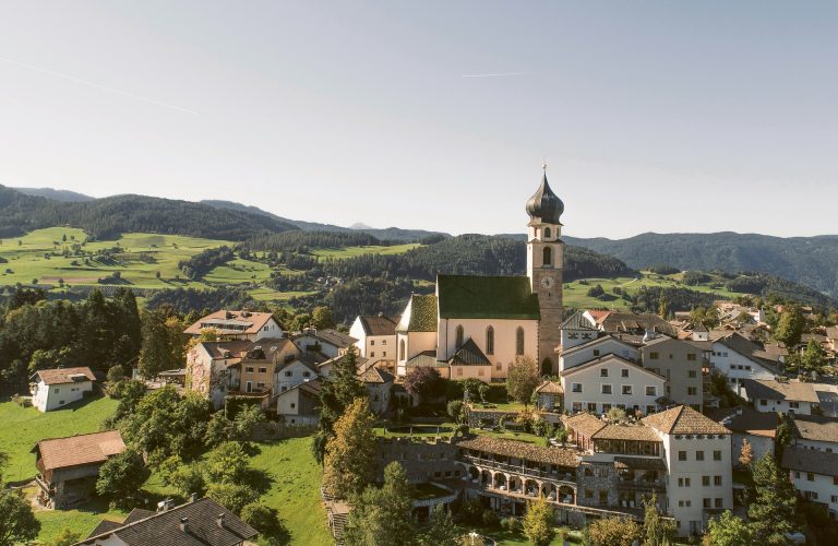 Außenansicht mit Kirchturm mit Blick auf das Romantik Hotel Turm in Völs in Südtirol